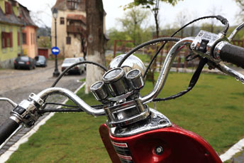雨に濡れるバイクの後ろには製靴職人の塔が